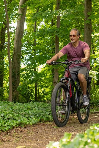 Man on e-bike cycling through a forest.